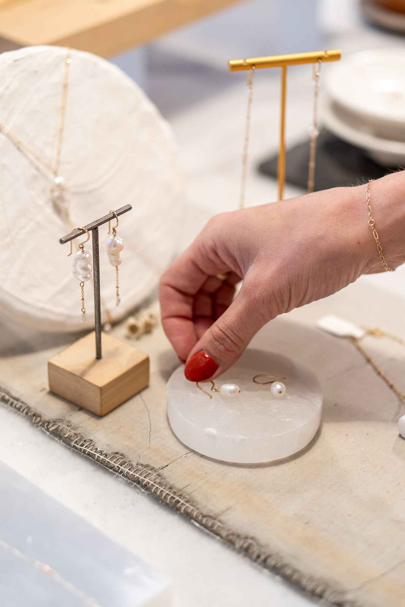 A woman showcasing pearl jewelry on a table, a popular choice among best sellers.