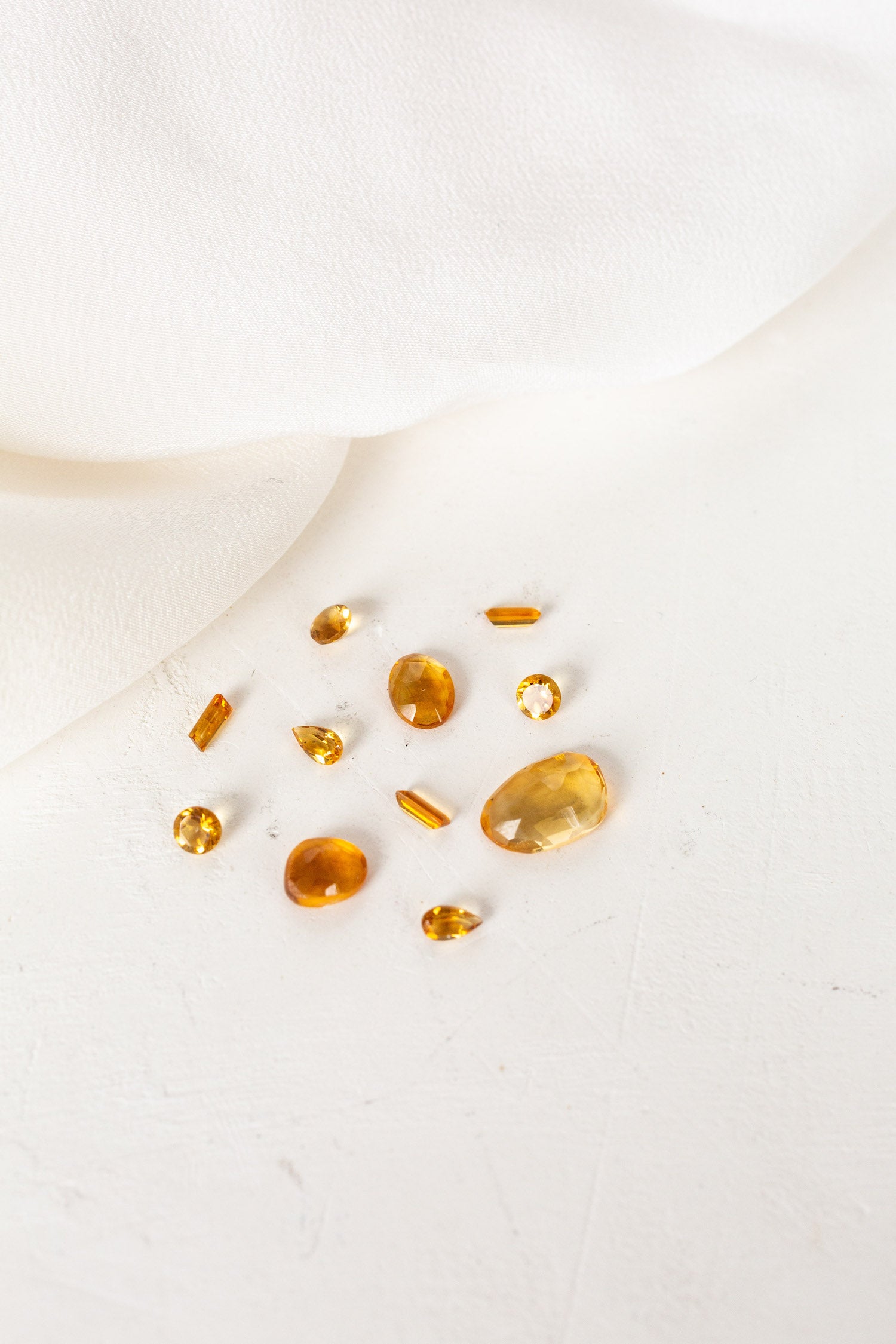 A group of yellow stones on a white cloth, representing November birthstones Citrine.