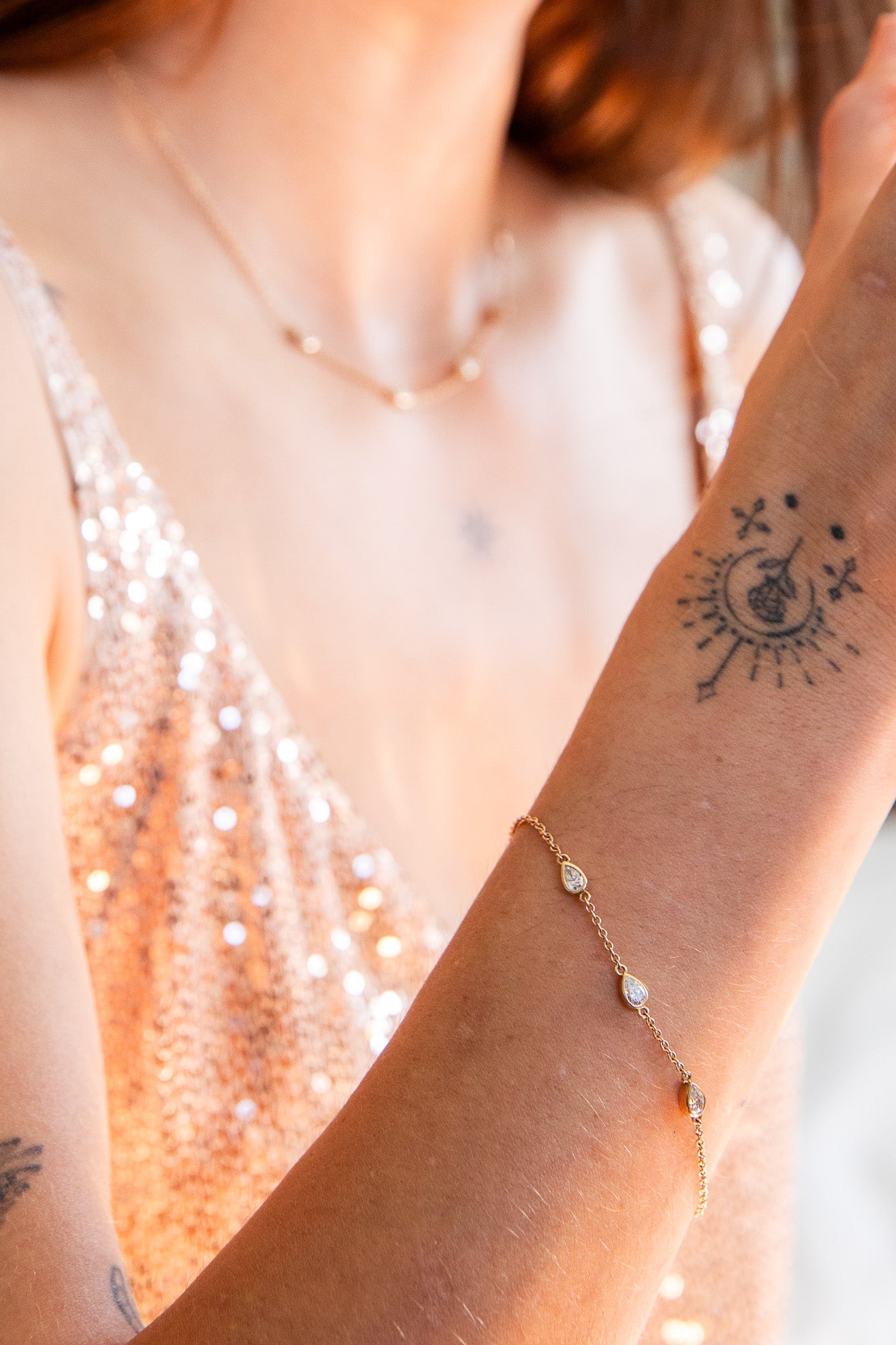 Woman wearing an Elaine B Jewelry Gemma Poolside Ring and an X Orbit Ring while holding champagne.