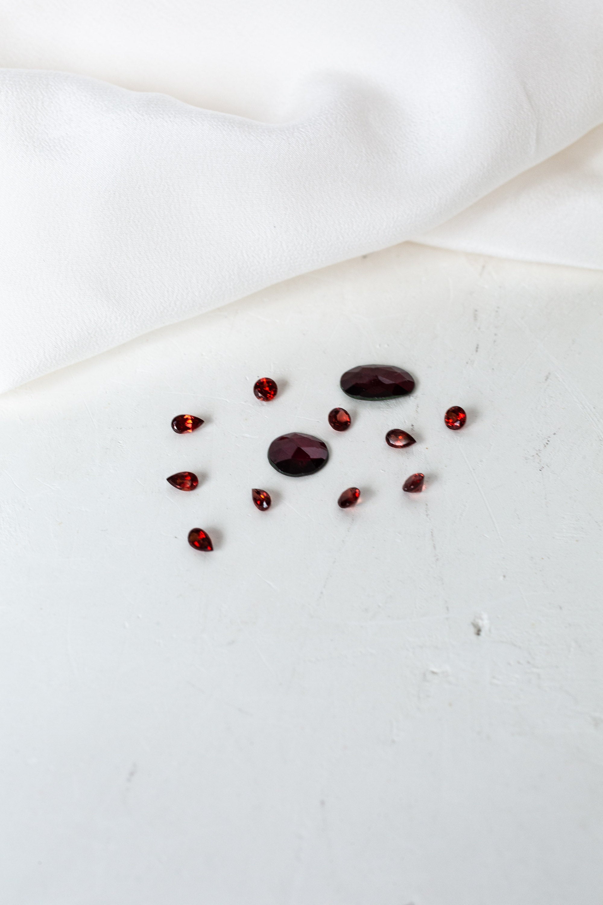 A white cloth adorned with red garnet birthstones.
