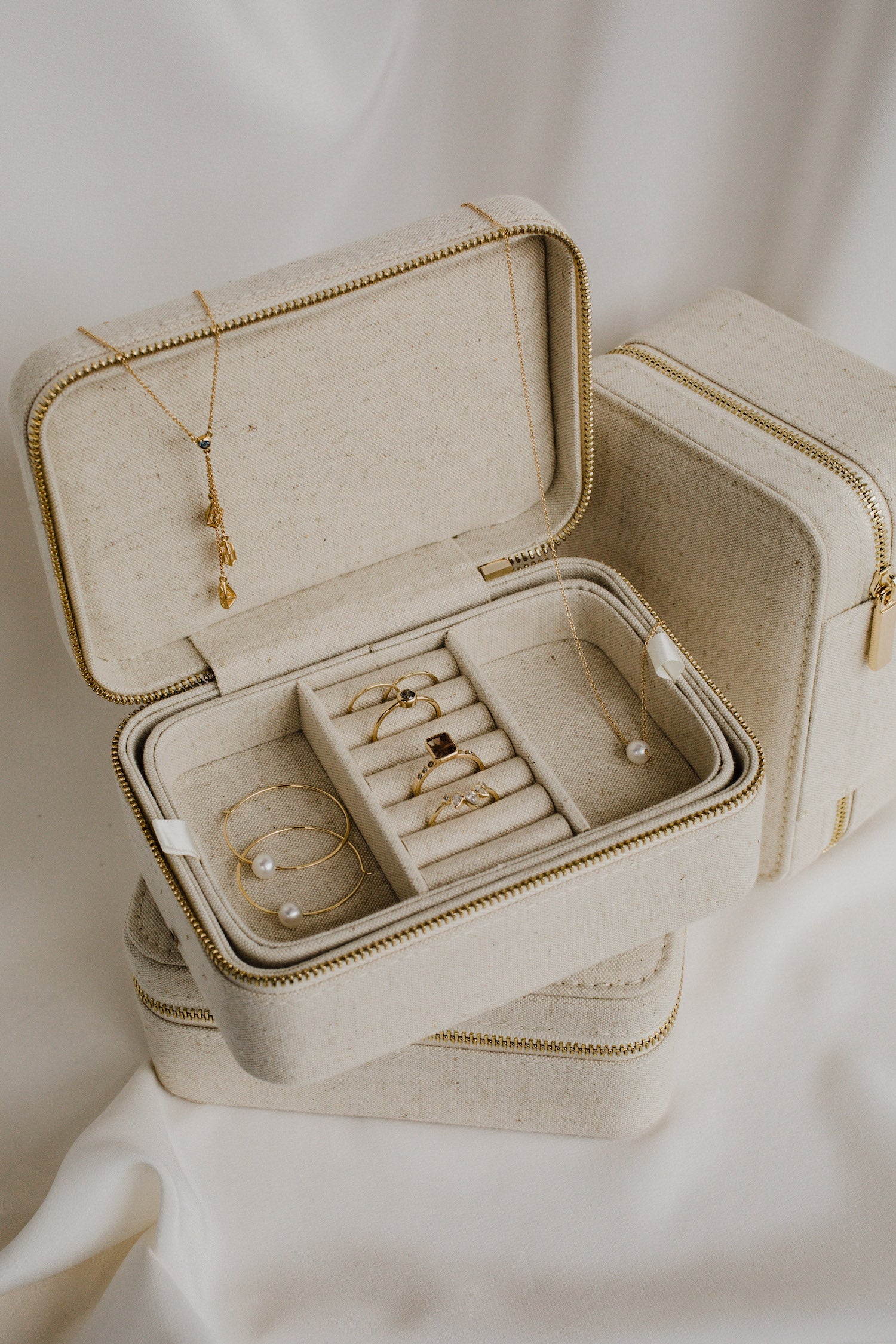 An off-white jewelry box filled with gold chains and rings, showcasing elegance and luxury.