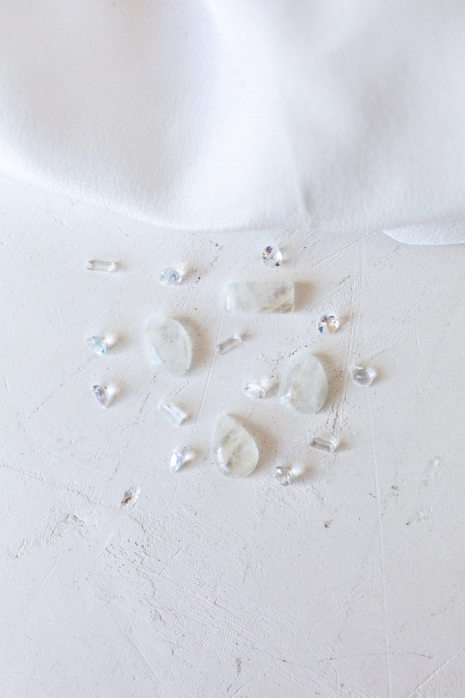 A white cloth adorned with pearls and moonstones, representing birthstones, arranged together