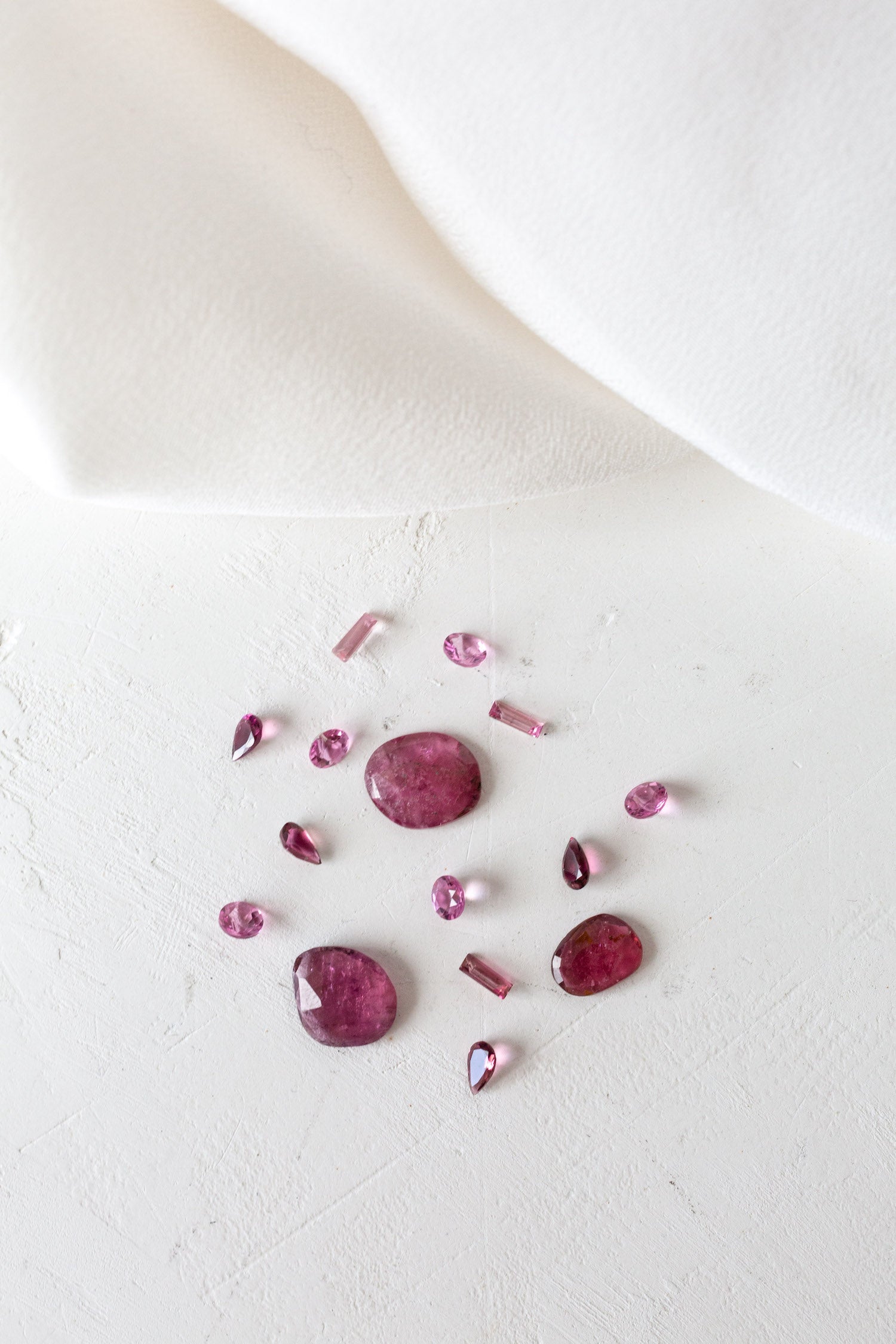 Pink Opal and Tourmaline birthstones on white surface, representing October birth month.