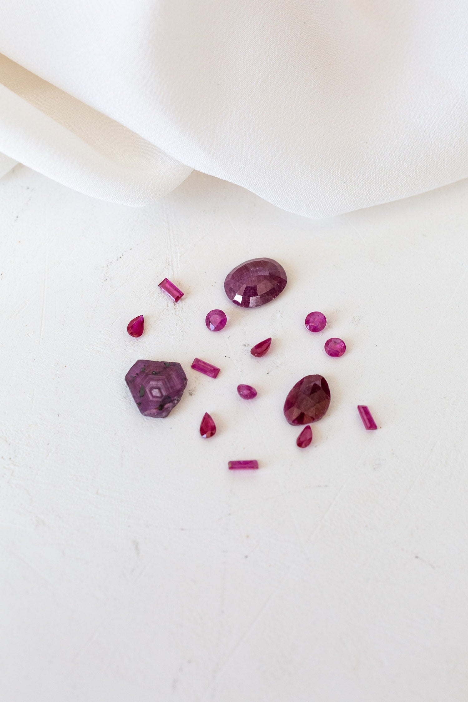 Deep Red stones and a white cloth, representing Ruby birthstones for July.