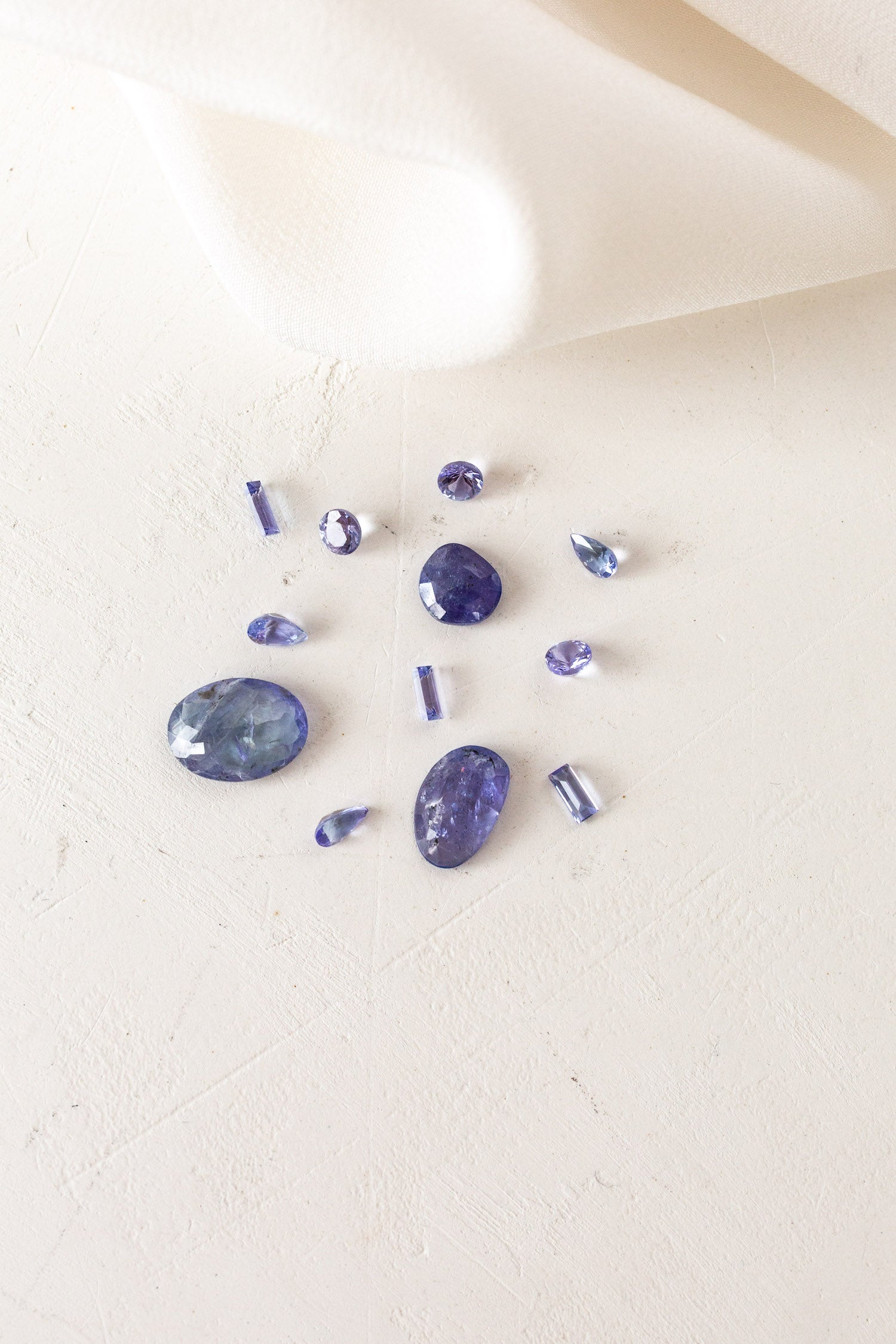 A group of purple stones on a white cloth, December Birthstones Tanzanite.