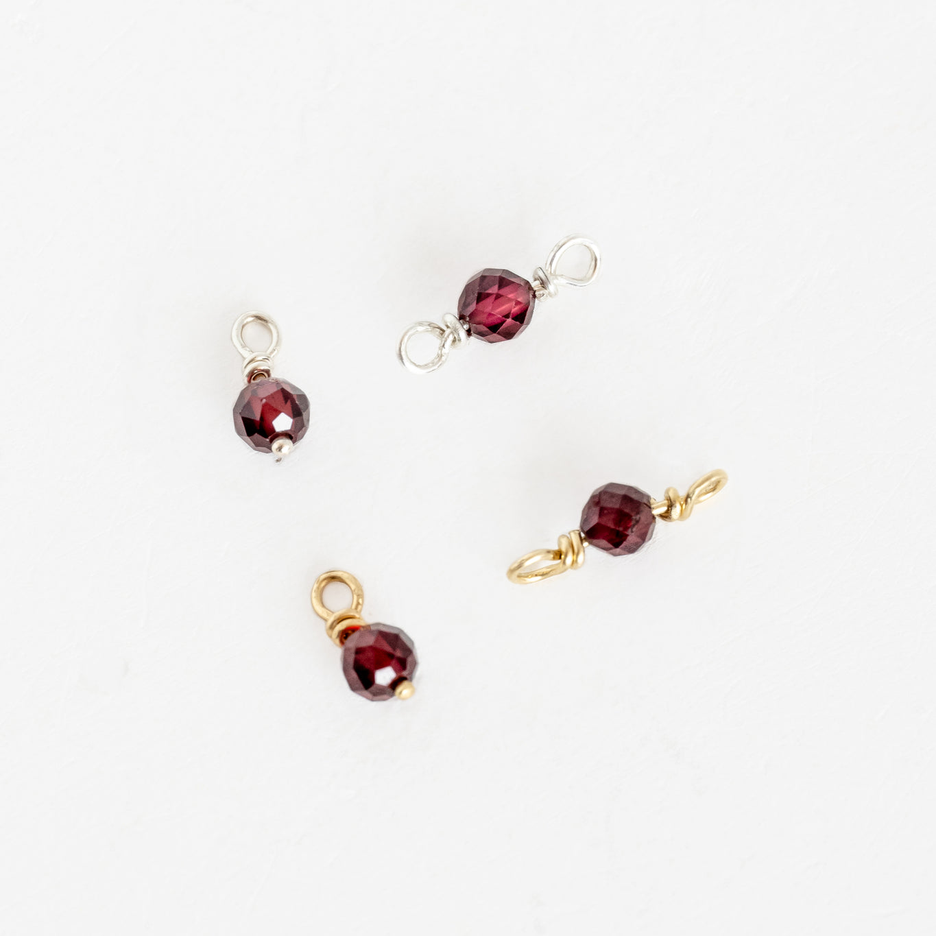 Four types of garnet beads on white surface, Forever Linked Birthstone Link or Dangle Charms.