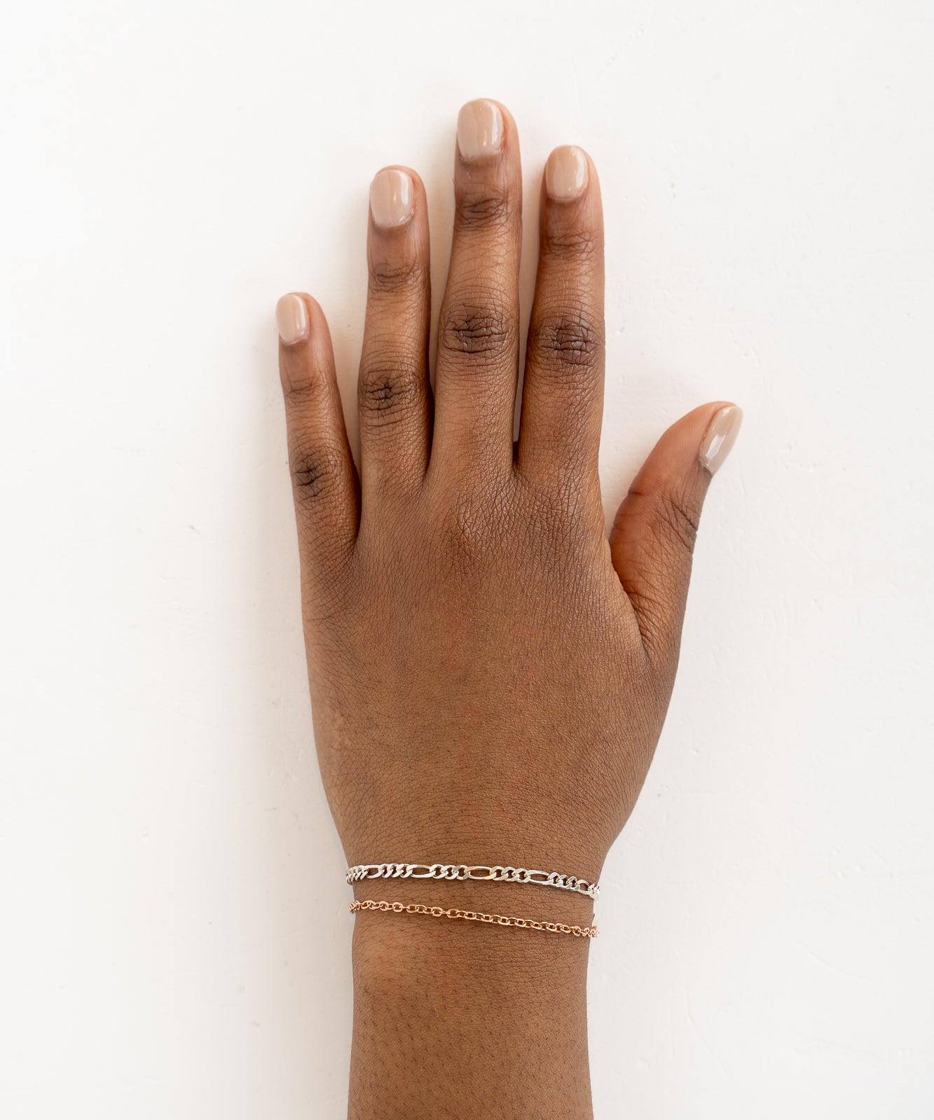 A woman's hand adorned with two delicate silver and gold bracelets, adding a touch of modern elegance