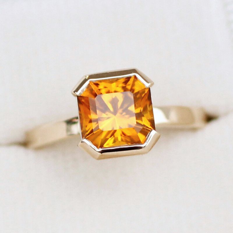A custom yellow diamond ring with a vibrant orange stone, showcasing unique and exquisite craftsmanship.