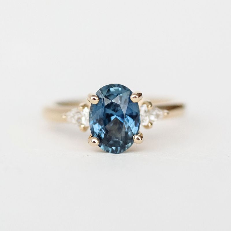 An elegant custom jewelry piece featuring an oval blue sapphire and diamond ring.