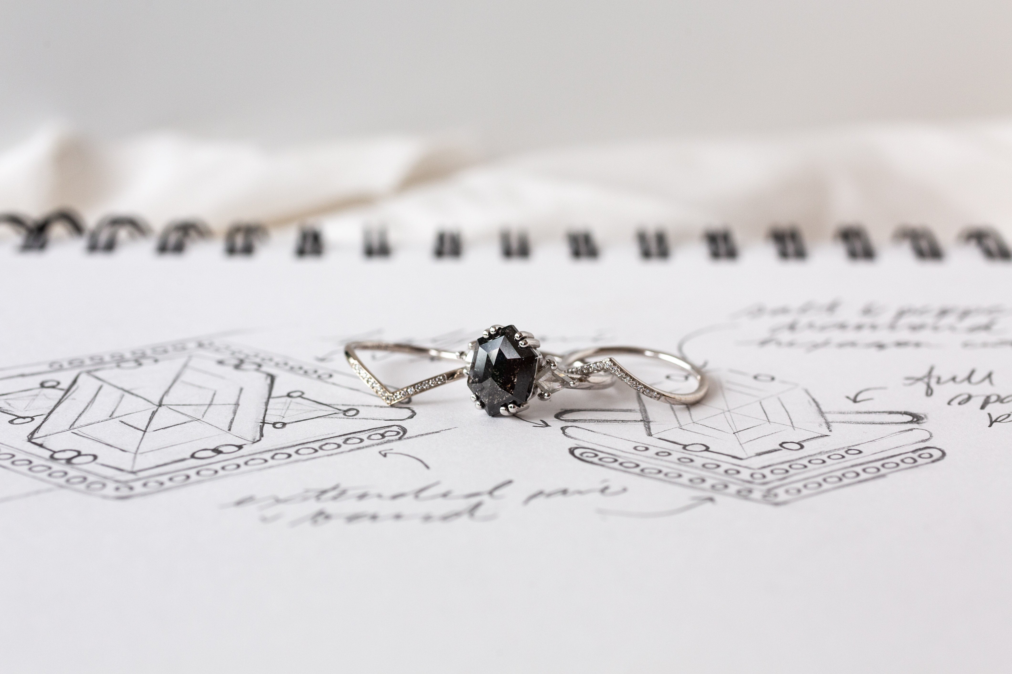 A custom engagement ring featuring a black stone, elegantly depicted in a drawing.