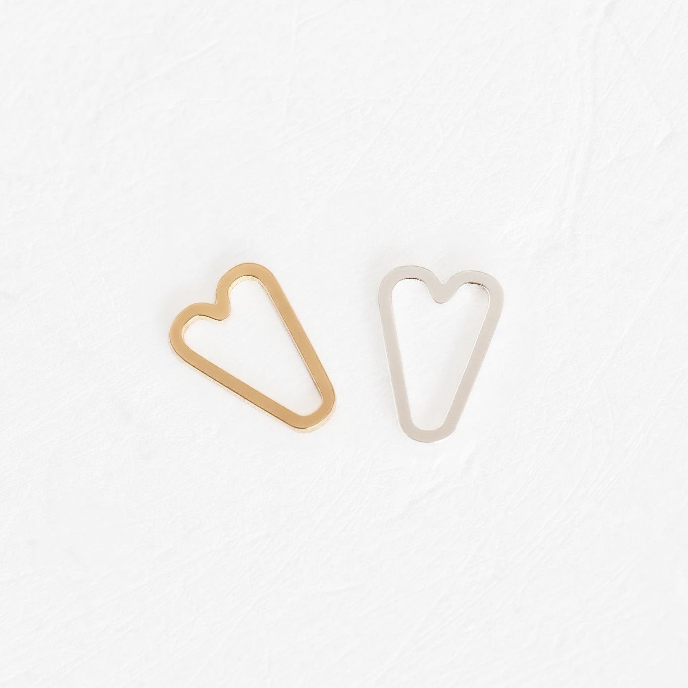 Two small heart-shaped clips on a white surface, representing Forever Linked Charms.