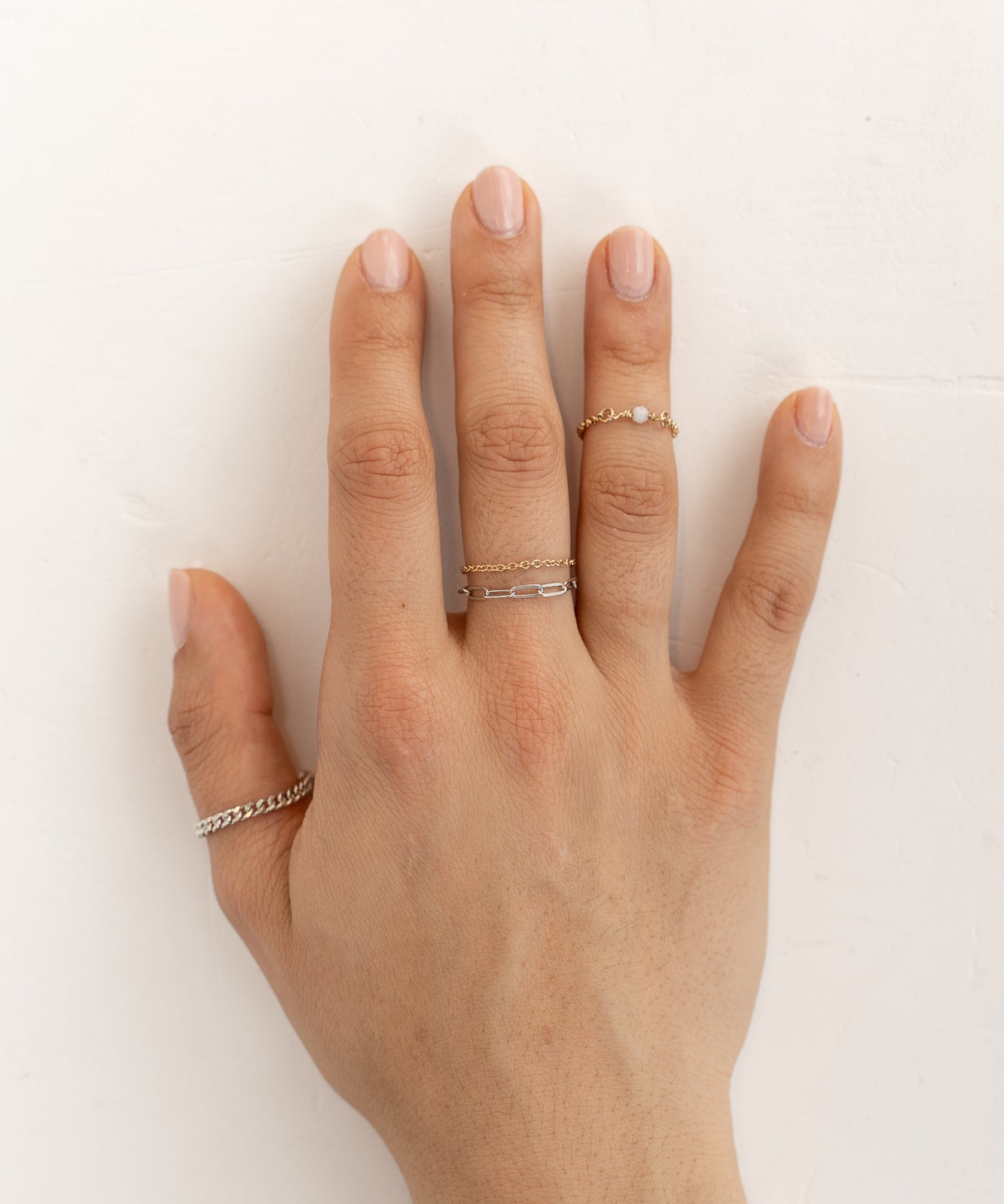 A hand adorned with four unique, Forever Linked chain rings