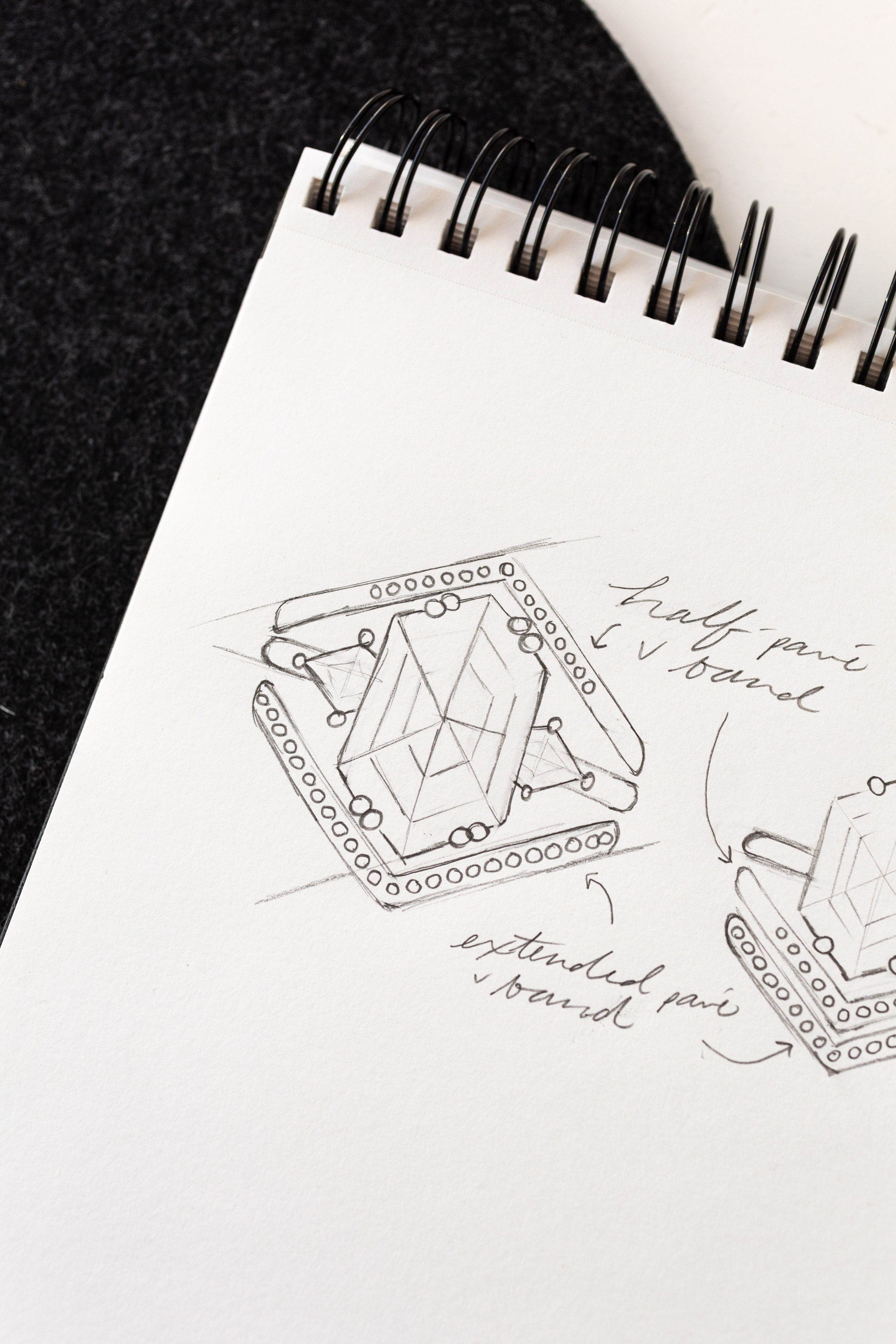 A sketch of a custom jewelry ring placed on a notebook, showcasing intricate design and craftsmanship.