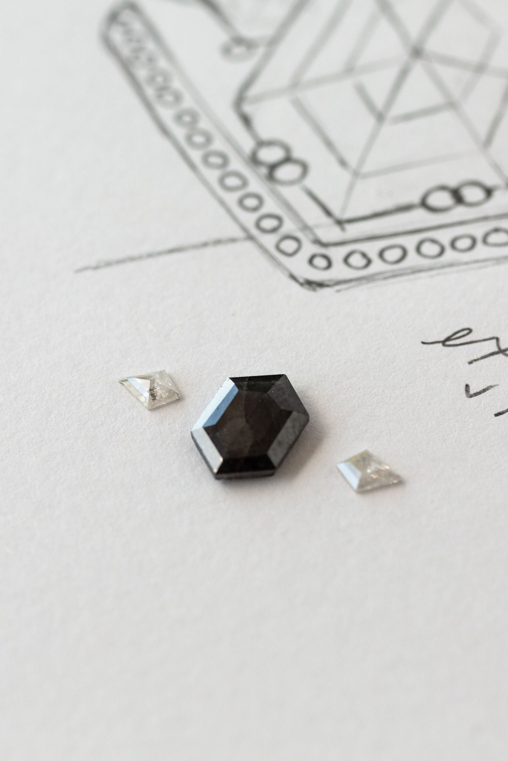 A black diamond on white paper, showcasing custom jewelry.