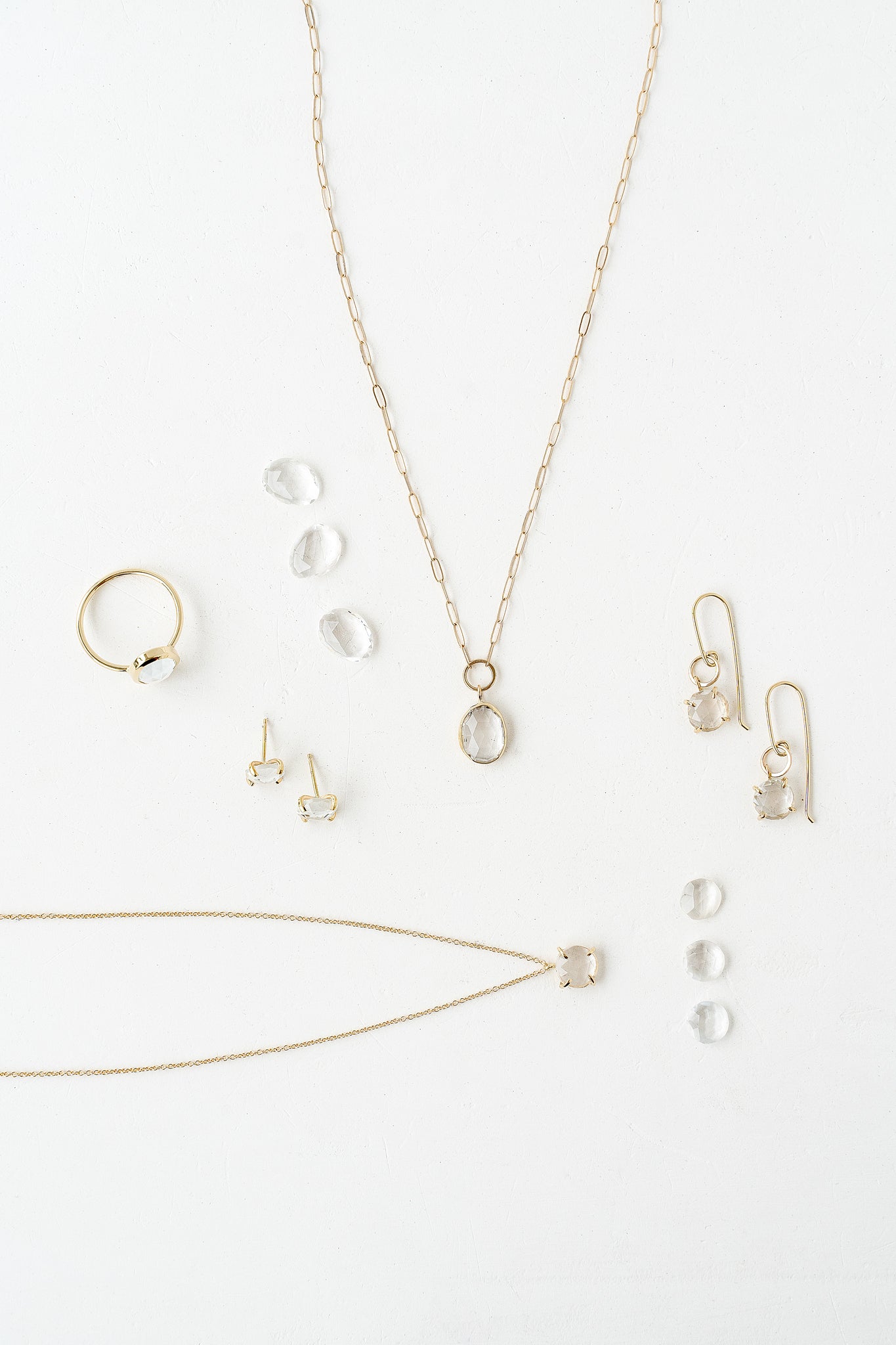 A stunning collection of jewelry featuring a necklace, earrings, and a ring with Diamond and White Topaz birthstones.