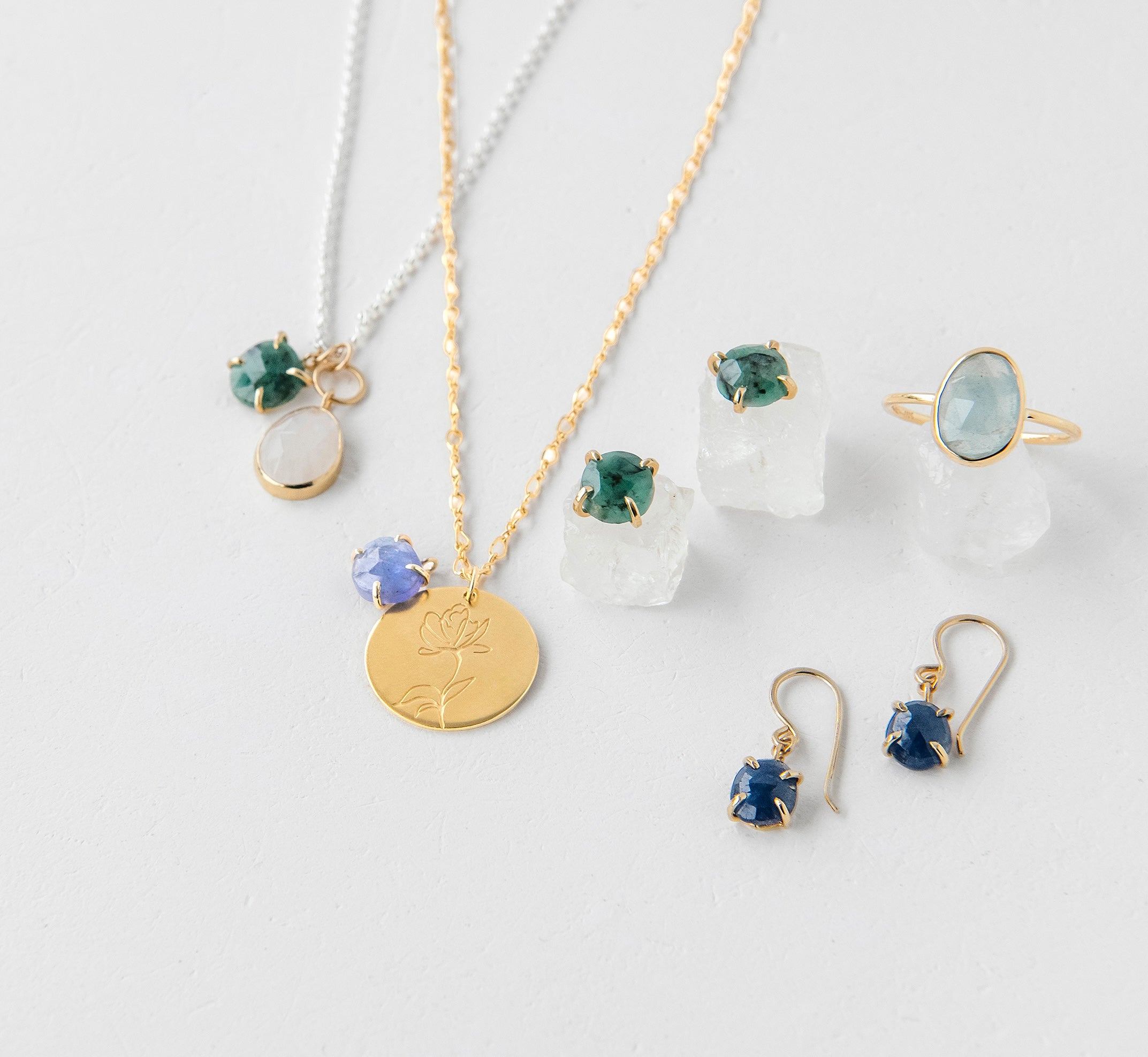 A vibrant assortment of gemstones and jewelry from the Elements collection, featuring birthstone designs.