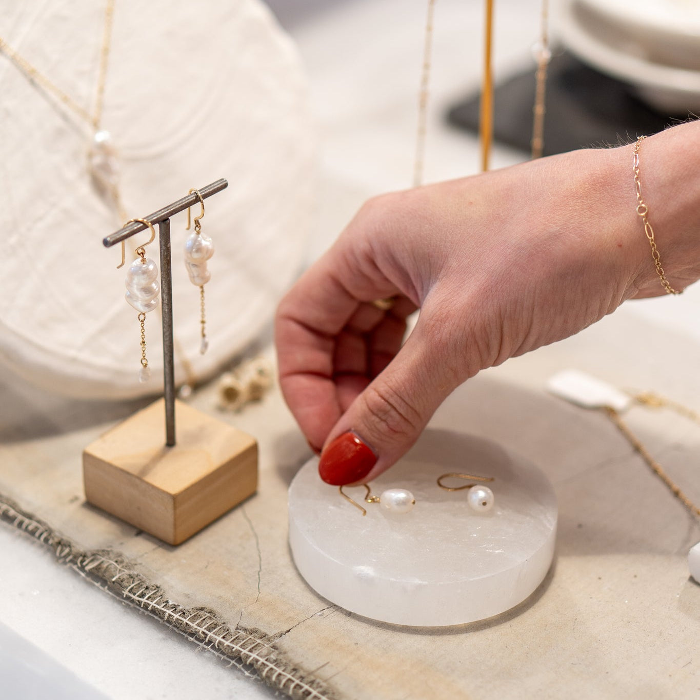 A woman showcasing pearl jewelry on a table, a popular choice among best sellers.