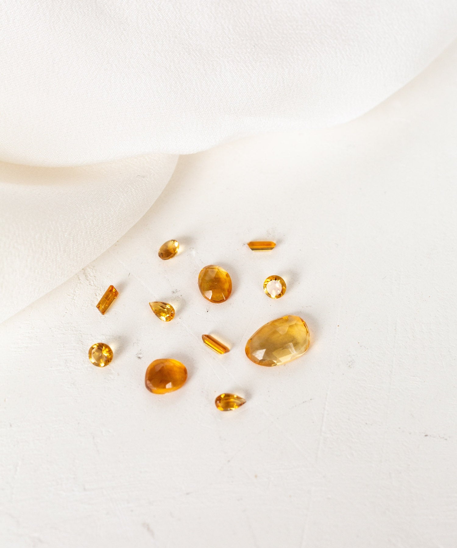A group of yellow stones on a white cloth, representing November birthstones Citrine.