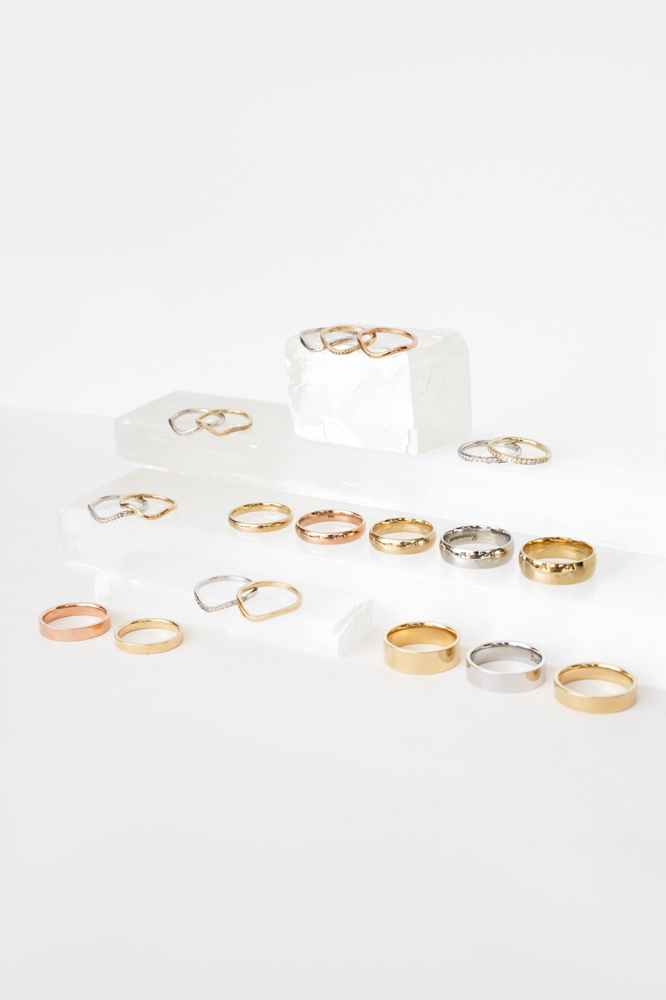 A minimalist collection of gold and silver rings displayed on a white surface.