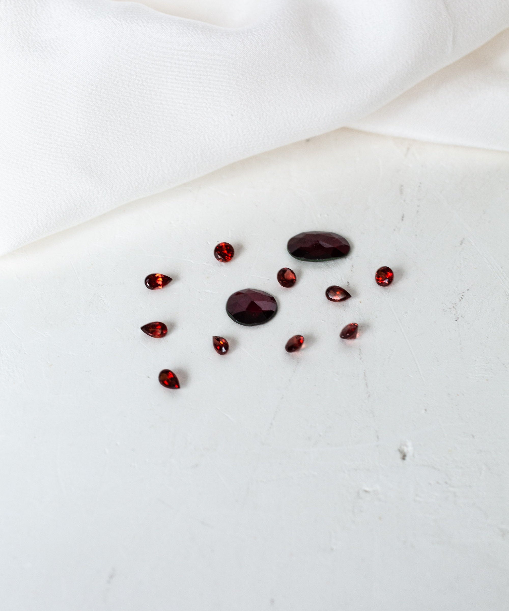 A white cloth adorned with red garnet birthstones.