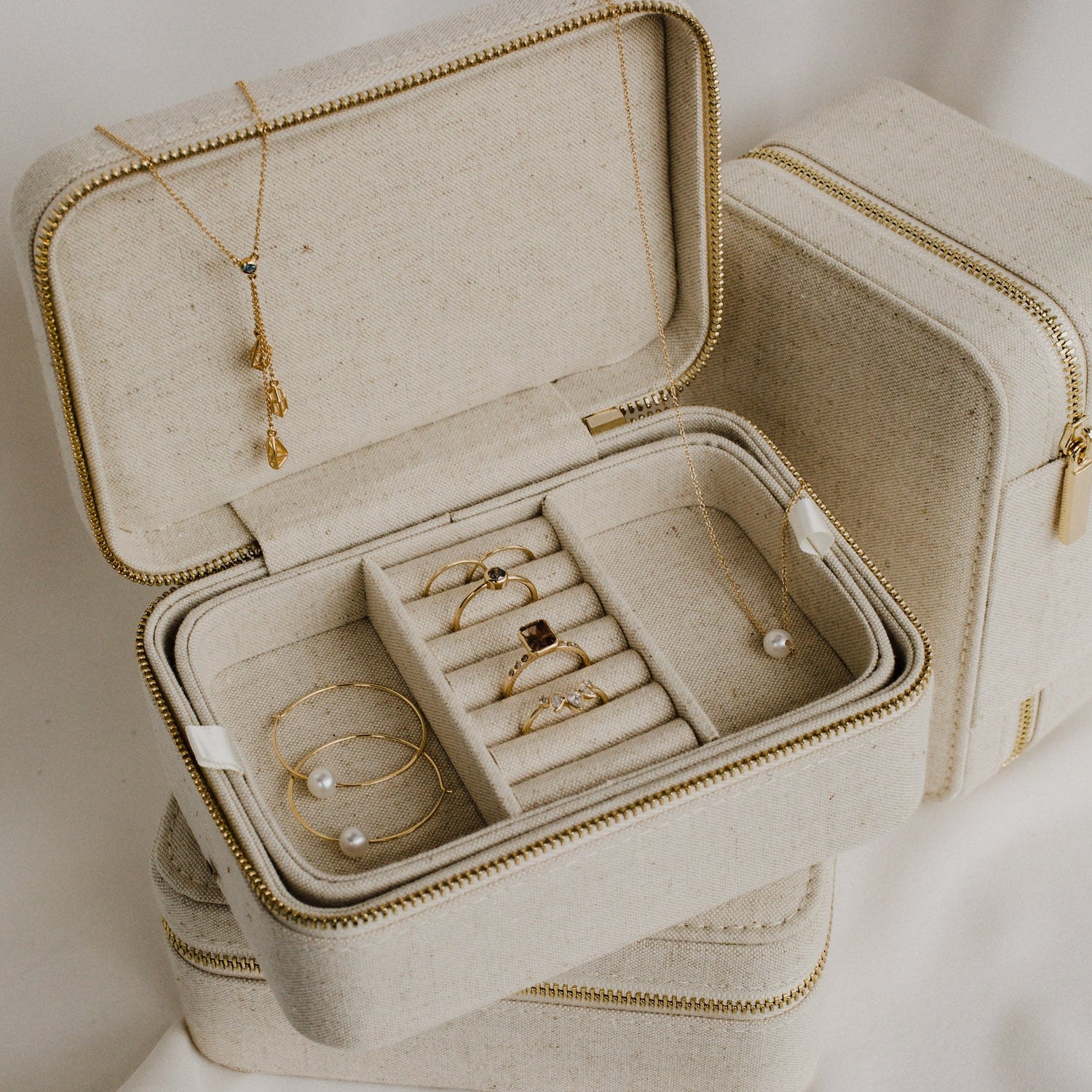 An off-white jewelry box filled with gold chains and rings, showcasing elegance and luxury.