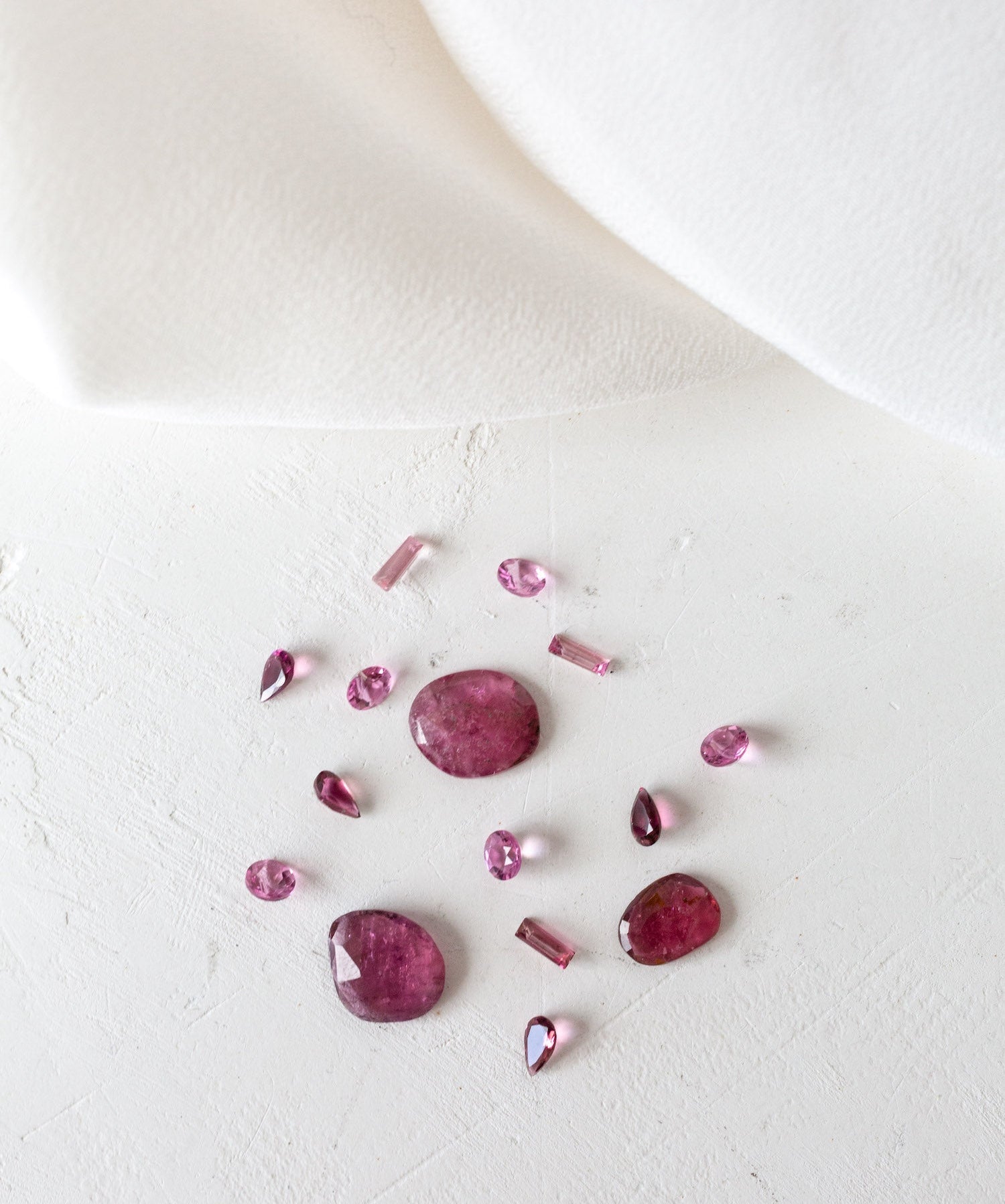 Pink Opal and Tourmaline birthstones on white surface, representing October birth month.