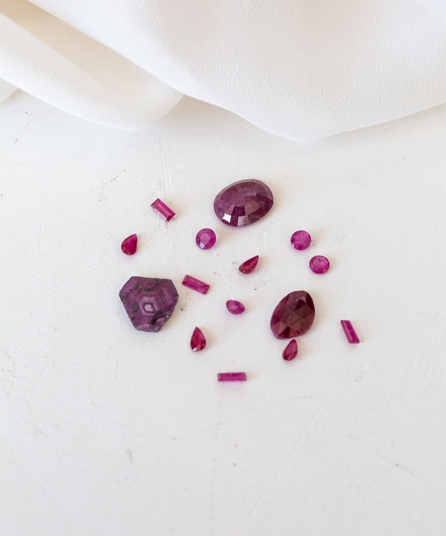 Deep Red stones and a white cloth, representing Ruby birthstones for July.