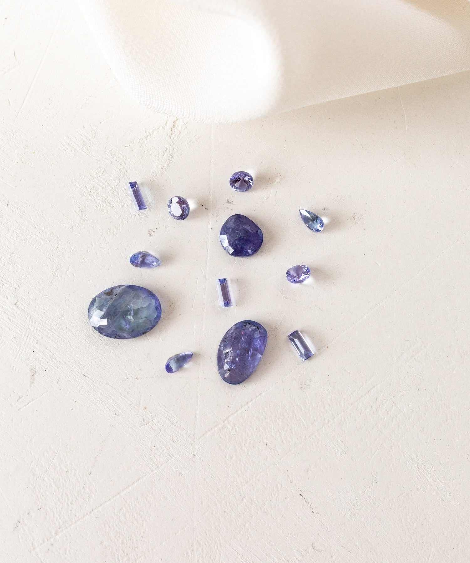 A group of purple stones on a white cloth, December Birthstones Tanzanite.