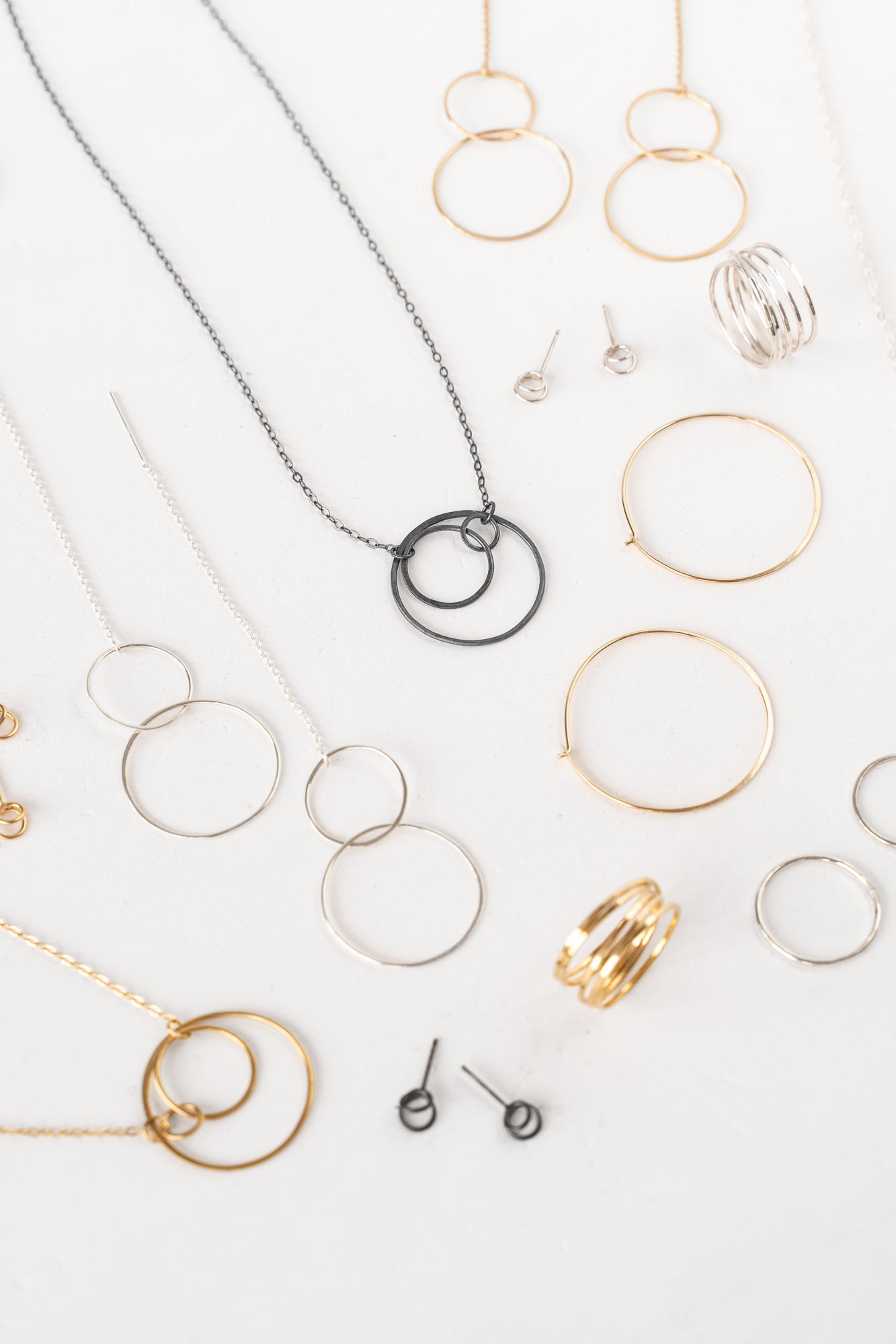 A collection of handmade silver and gold jewelry showcasing organic shapes created by interconnected circles.