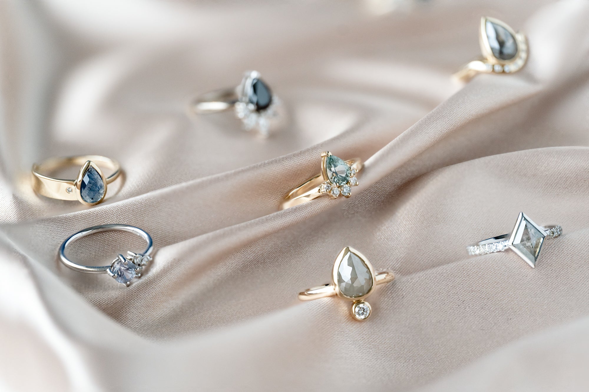Three alternative engagement rings displayed in white and blue velvet boxes.
