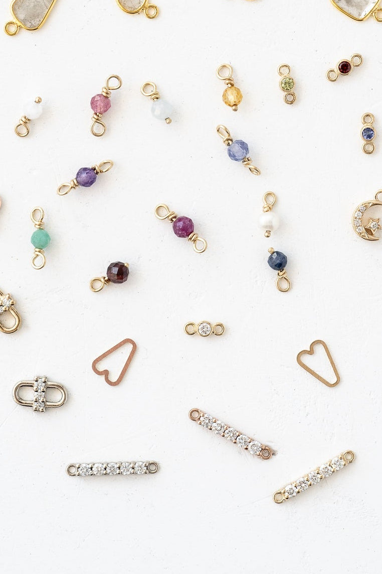 Various gold and silver jewelry, including charms, displayed in an assortment of styles and designs.