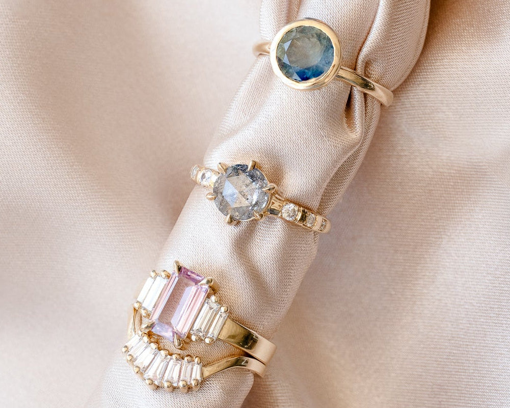 Gold rings with gemstones on a beige fabric background