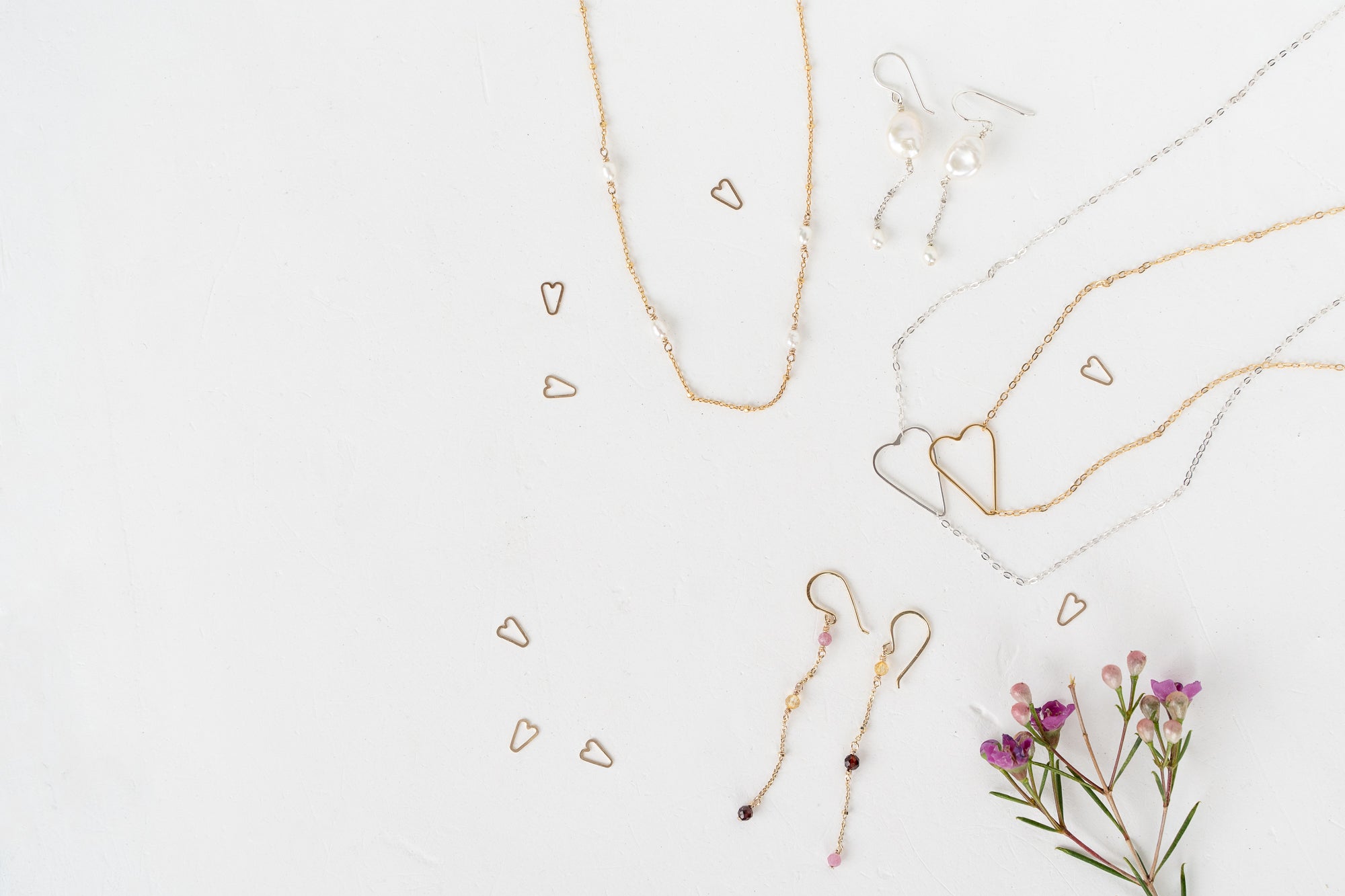 Gold jewelry set with heart-shaped pendants on a light background