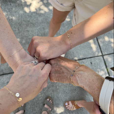 A multigenerational group of people holding hands in a circle, showcasing unity and teamwork.