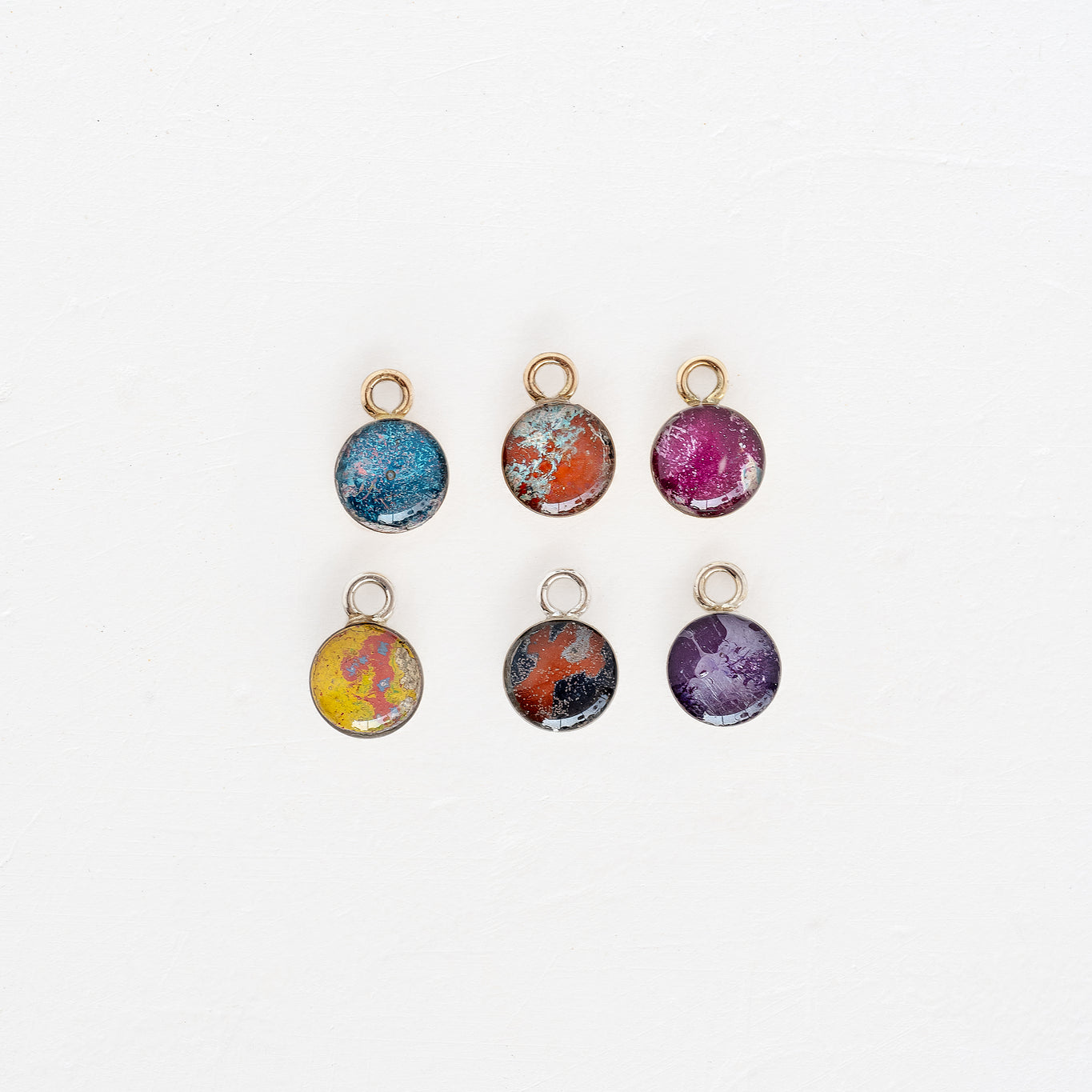 Six small round charms with different colors on them known as Rebel Nell