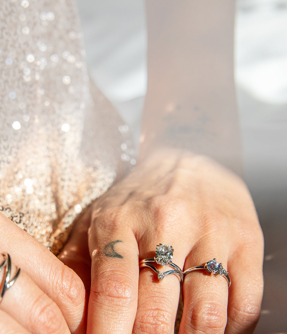 Close-up of hands wearing multiple Elaine B Jewelry rings with a blurred background