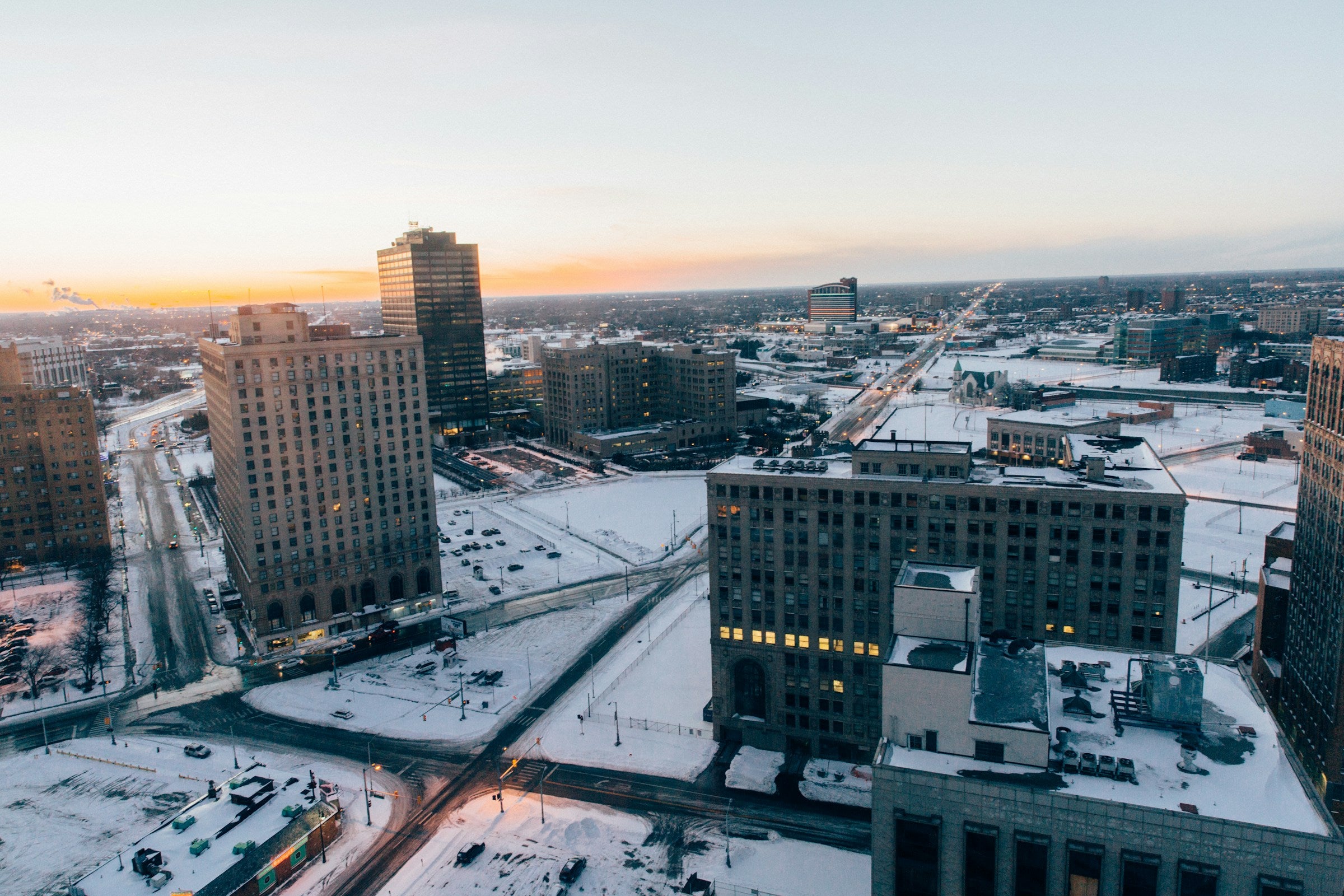 Cityscape of Detroit with snow-covered ground and buildings at sunset, showing Cass Corridor.  Photo by Laura Brain on Unsplash.